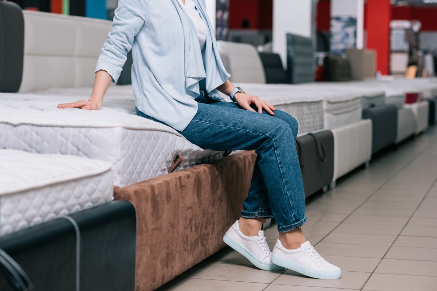 Partial View Of Woman Sitting On Mattress In Furniture Shop